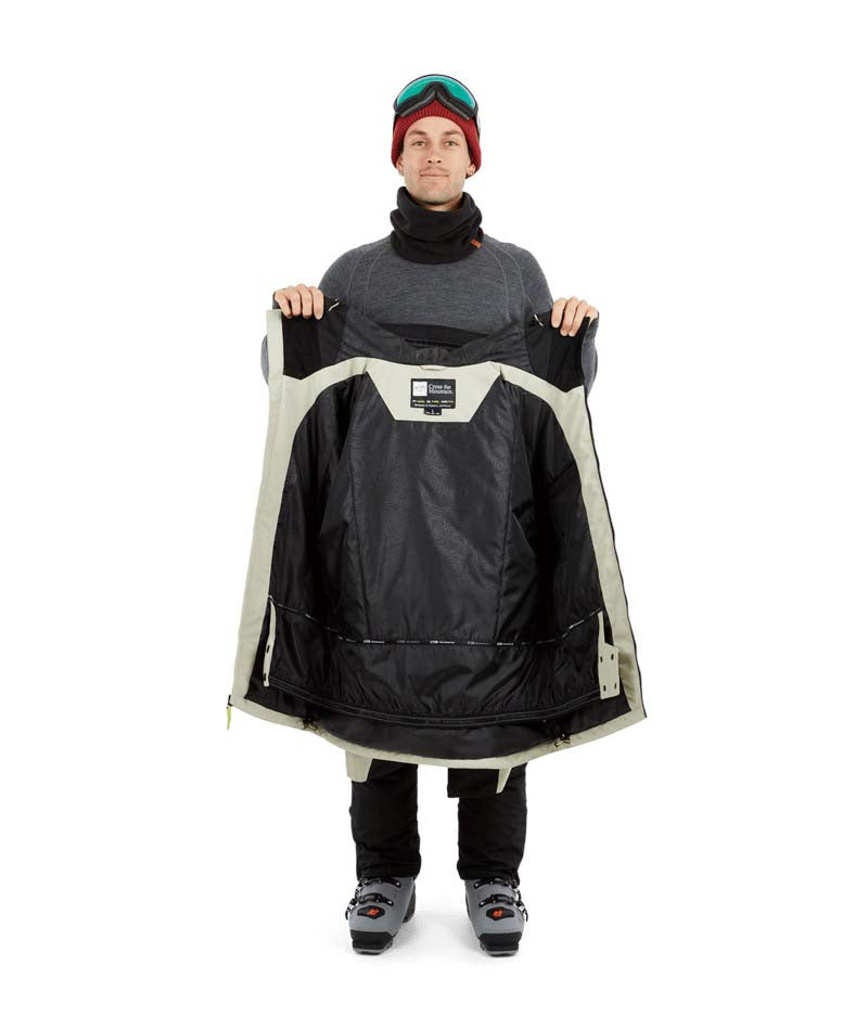 DescentJacket-A man wearing a black and off-white ski jacket with black gloves, a red knit beanie, and ski goggles, photographed against a solid white background.