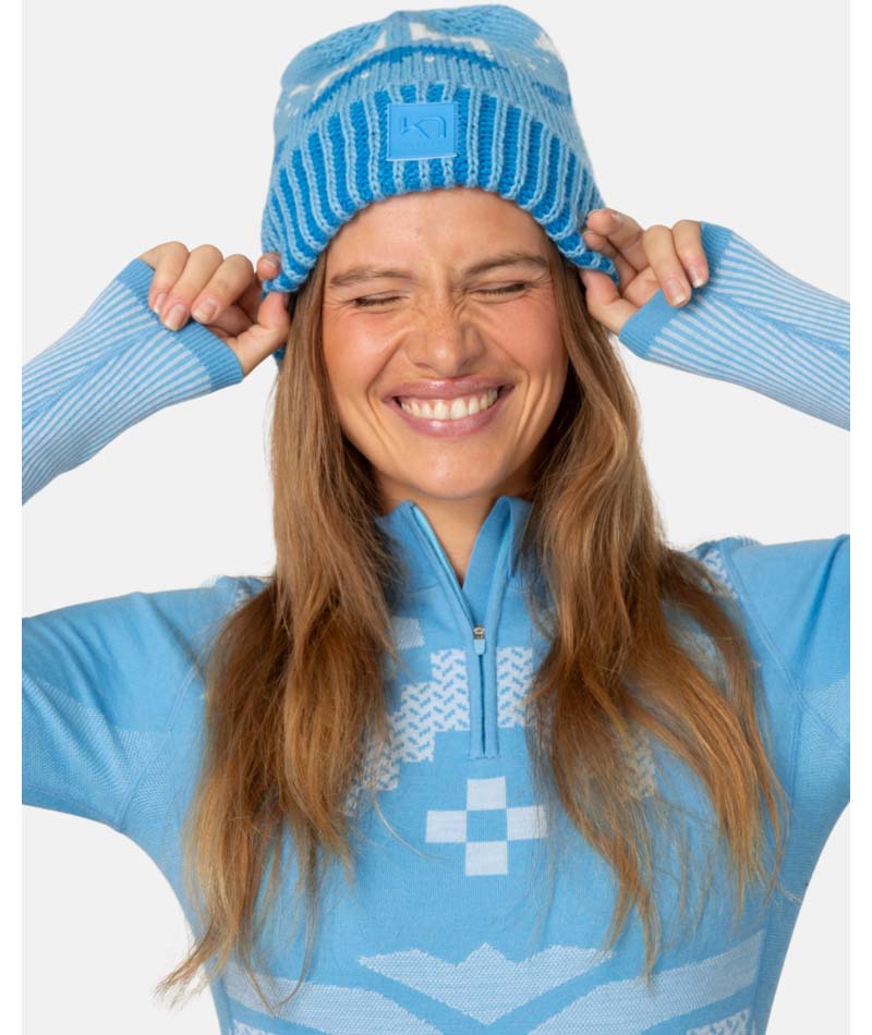 FaithBeanie-Woman wearing a blue ski suit with matching hat on a white background