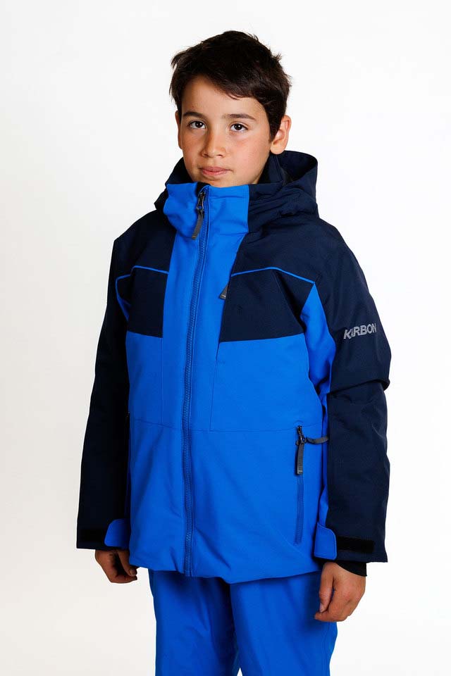 KrakenBoysInsulatedJacket-A young boy wearing a blue and navy Karbon ski jacket and matching blue ski pants, standing against a plain white studio background.