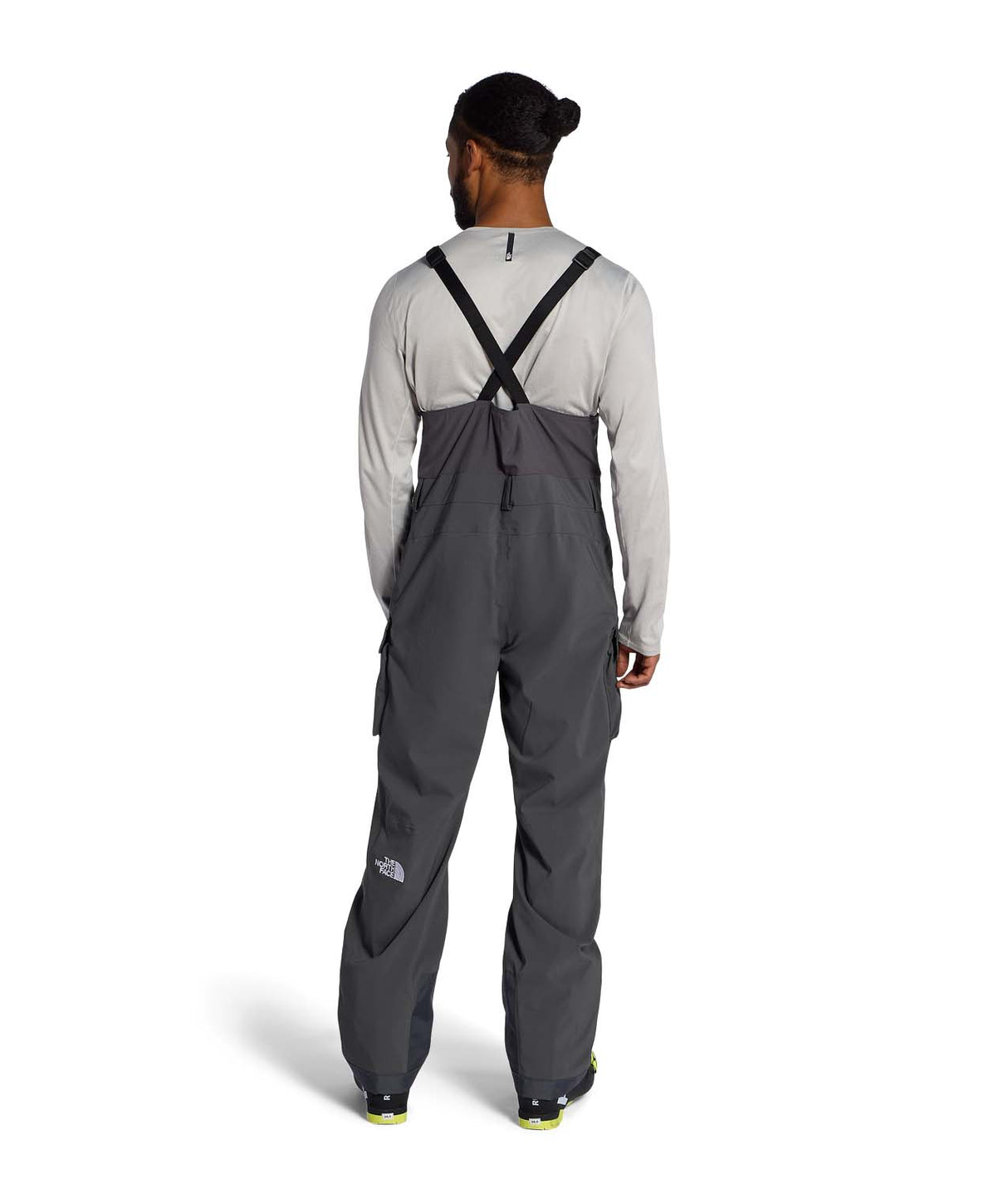 MFreedomBib- Man wearing grey bib overalls with The North Face logo on a white background