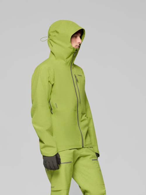 LofotenGore-TexJkt-Person wearing a green ski jacket on a gray background
