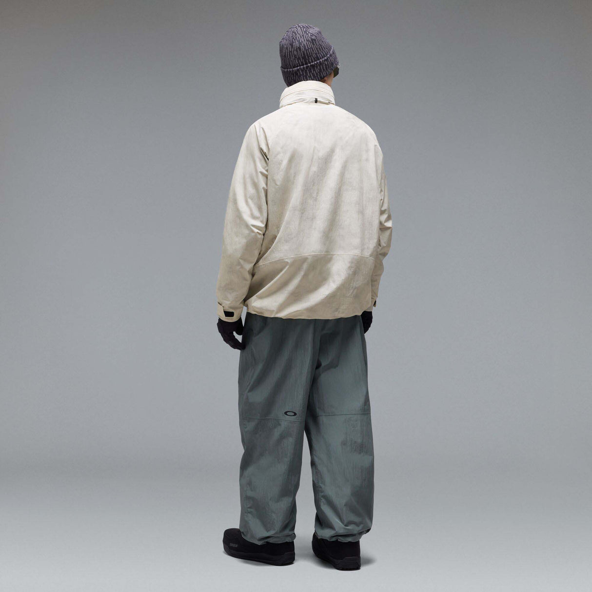 MMthodGlowShellJacket-A light beige technical jacket with black zippers, black piping details, and an Oakley logo on the left chest, displayed against a neutral gray background.