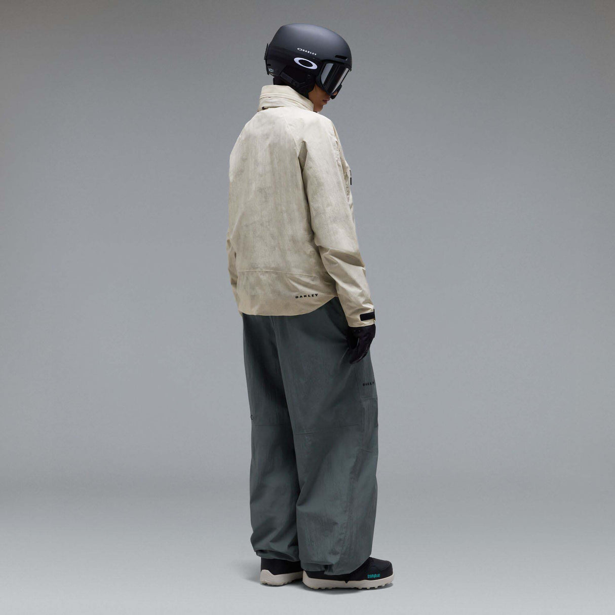 MMthodGlowShellJacket-A light beige technical jacket with black zippers, black piping details, and an Oakley logo on the left chest, displayed against a neutral gray background.