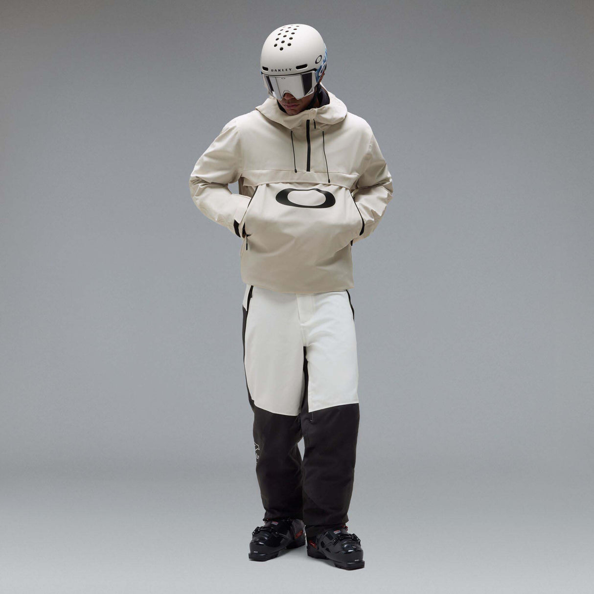 MTimberlineShellAnorak-An off-white hooded anorak jacket with a large black Oakley logo on the chest, displayed against a neutral gray gradient background.