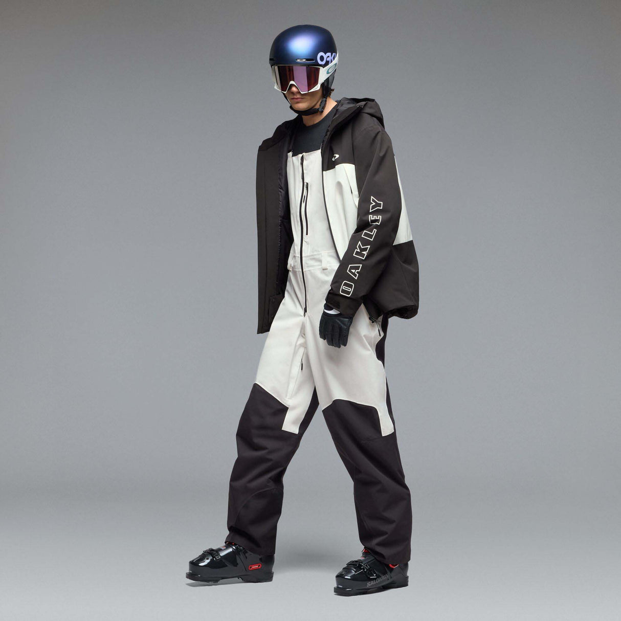MTimberlineShellBib-A white and black technical snow bib with adjustable shoulder straps, a front zipper, and reinforced lower leg panels, shown against a neutral gray gradient background.
