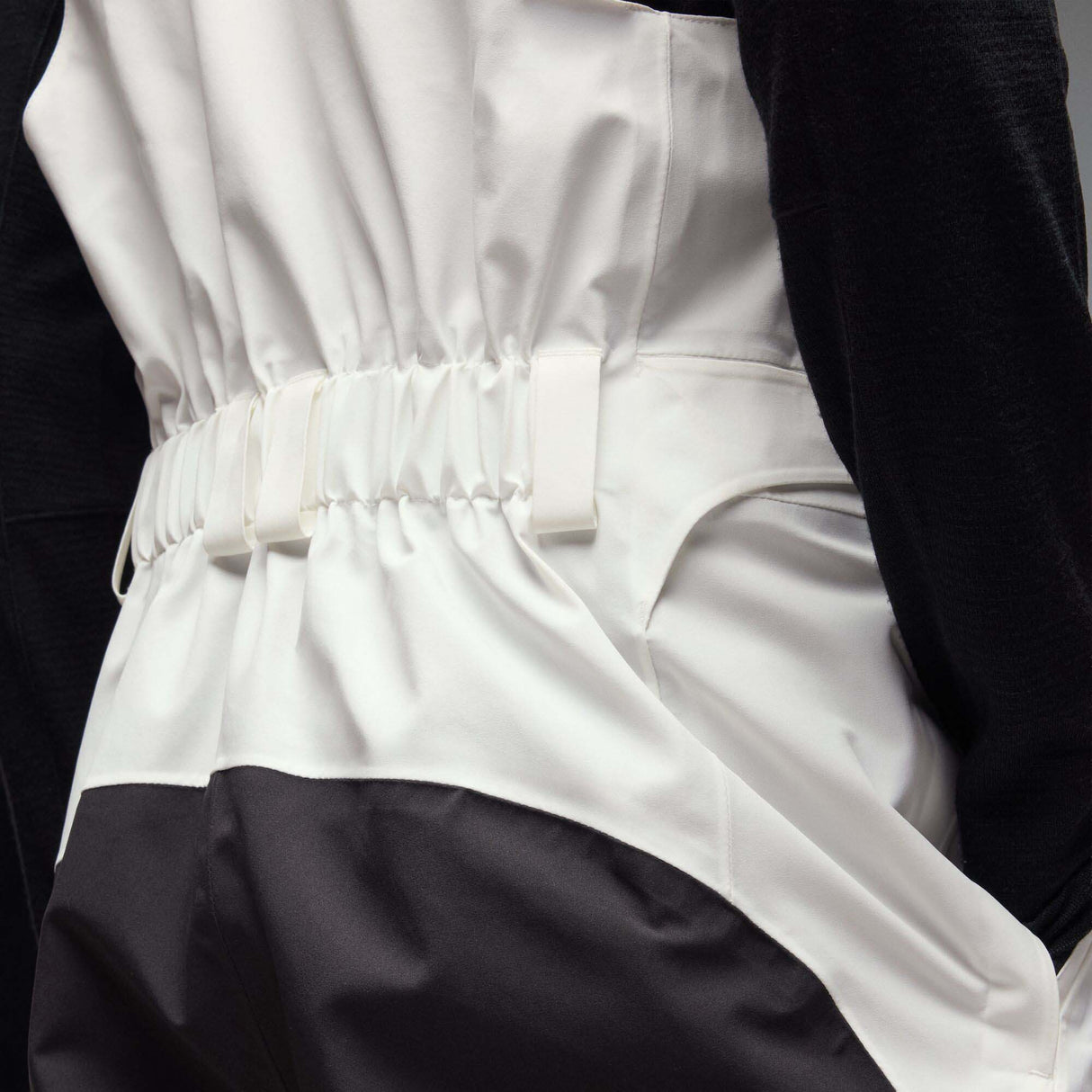 MTimberlineShellBib-A white and black technical snow bib with adjustable shoulder straps, a front zipper, and reinforced lower leg panels, shown against a neutral gray gradient background.