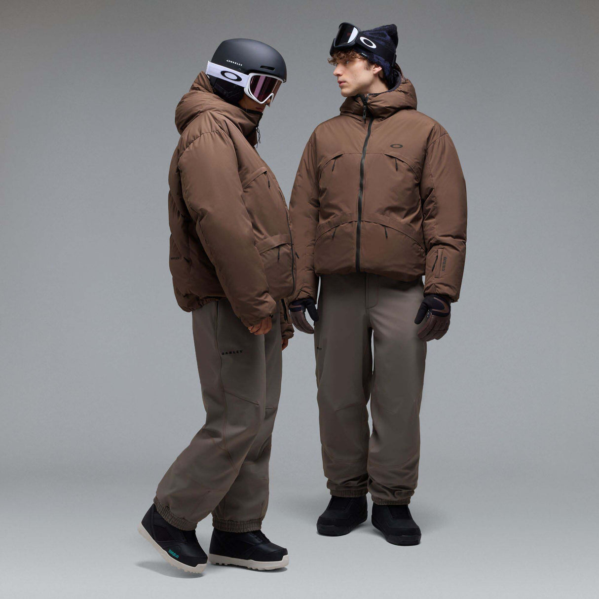 MWintertideSoftshellPant-A pair of gray snow pants with a black belt and a small black Oakley logo on the left thigh, displayed against a neutral gray gradient background.