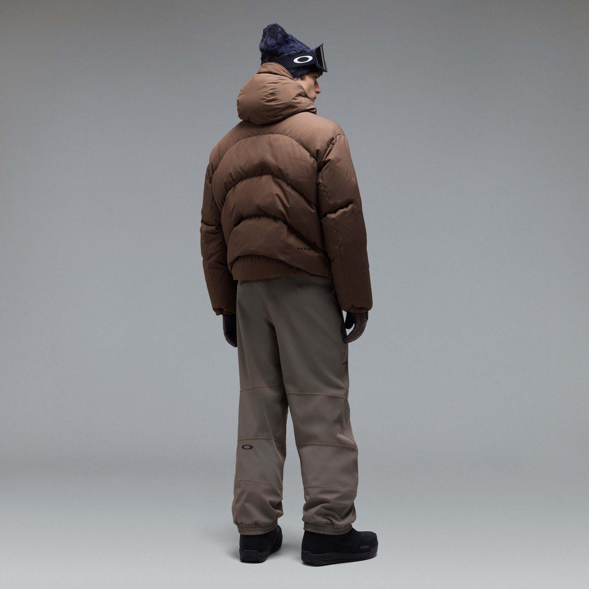 MWintertideSoftshellPant-A pair of gray snow pants with a black belt and a small black Oakley logo on the left thigh, displayed against a neutral gray gradient background.