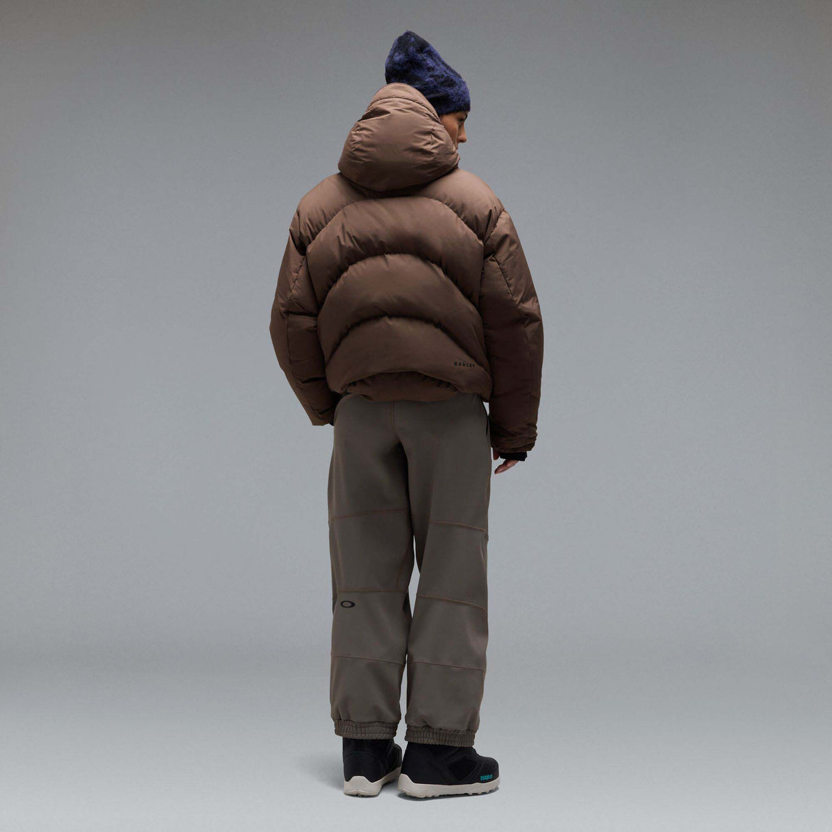 MWintertideSoftshellPant-A pair of gray snow pants with a black belt and a small black Oakley logo on the left thigh, displayed against a neutral gray gradient background.