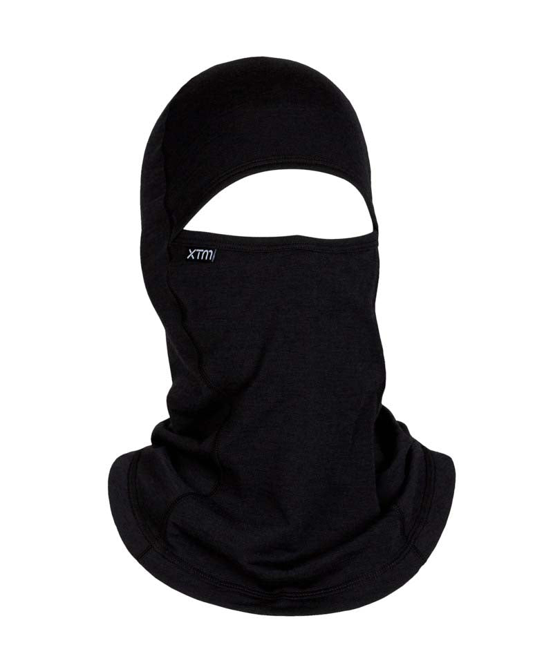 MerinoAdventureIIBalaclava-A black knit balaclava face mask with an eye opening, featuring a small white 'xtm' logo on the left side, shown against a plain white background.