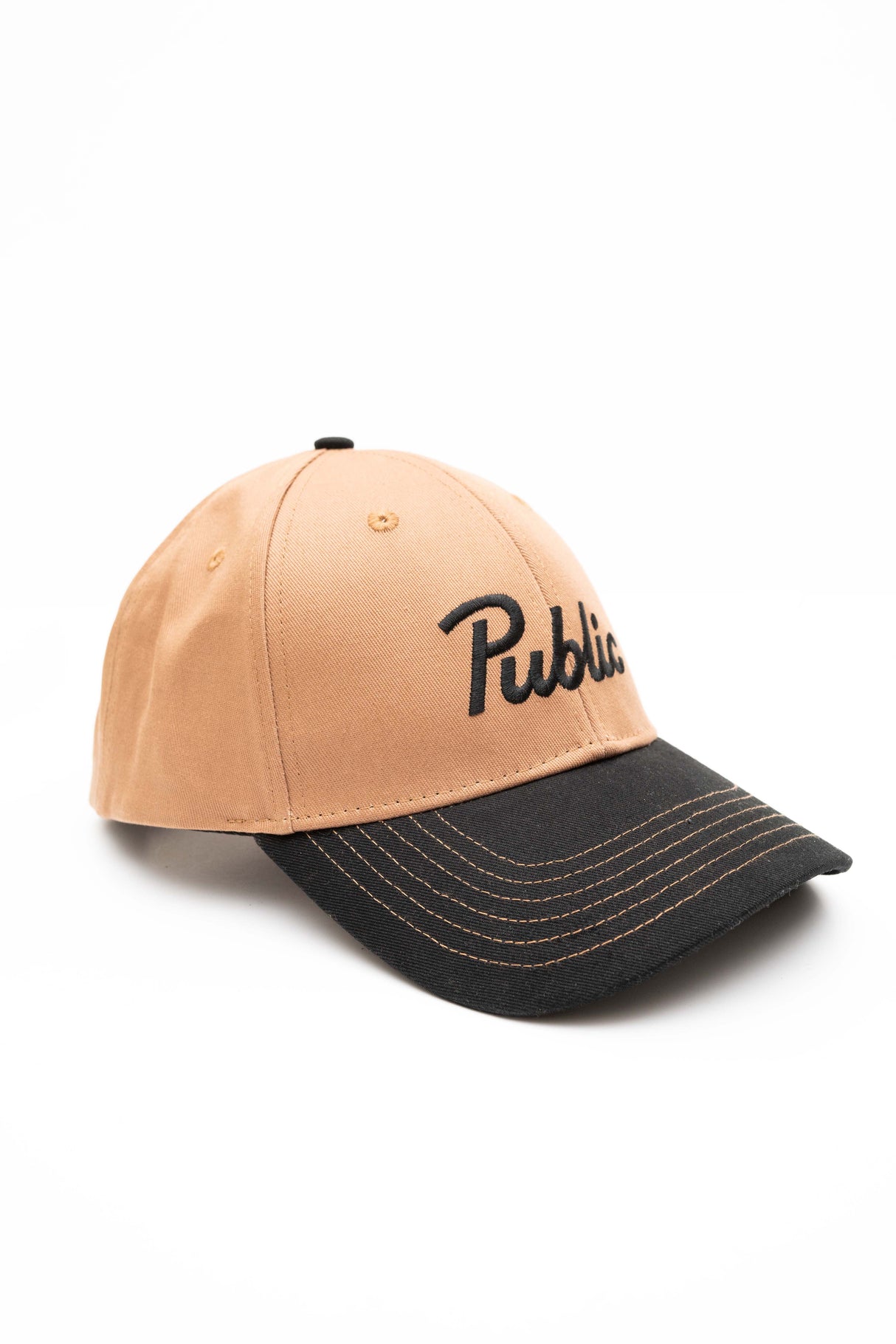 ScriptCap-A two-tone baseball cap with a tan crown and a dark charcoal gray brim, featuring the word 'Public' embroidered in black script across the front.