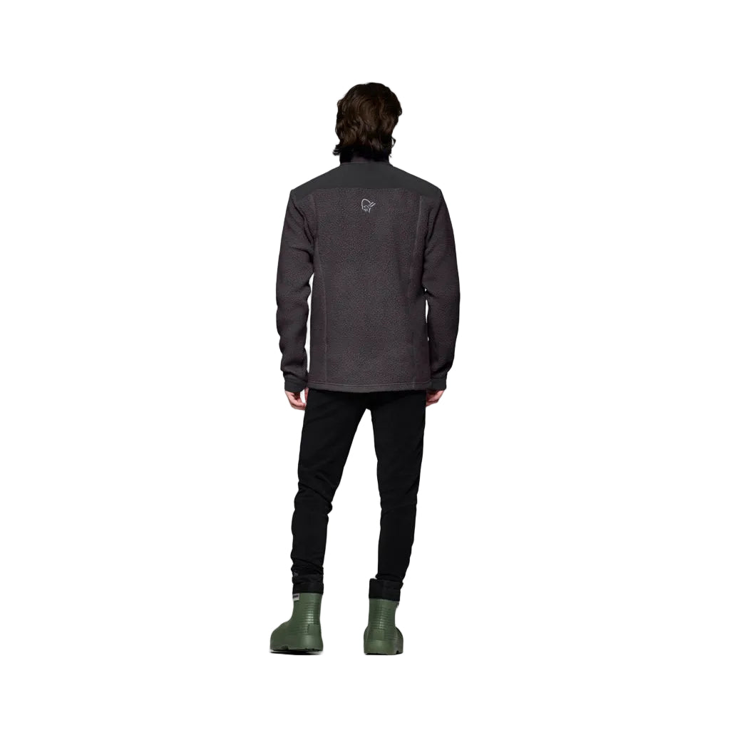 TrollveggenWarm3Jkt_-Person wearing a dark gray jacket, black pants, and green boots on a white background