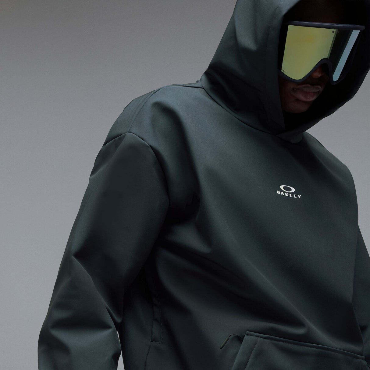 WintertideScratchedHoodie-A dark charcoal gray hooded sweatshirt with a small white Oakley logo on the left chest, displayed against a neutral gray gradient background.