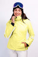 AthenaWomensInsulatedJacket-A woman wearing a bright yellow ski jacket with white side stripes, white ski pants, a black beanie, and blue ski goggles, posing against a light gray studio background.