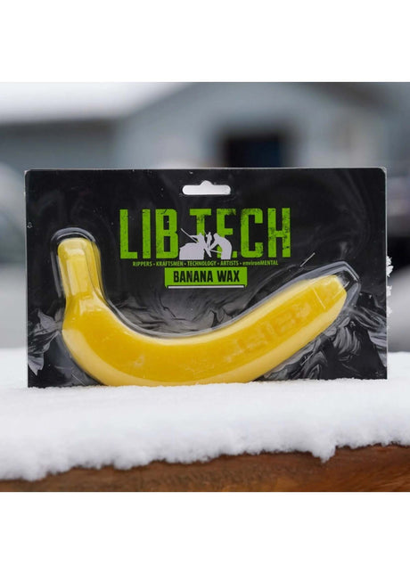 BananaWax- Lib Tech banana wax packaging on a snowy surface with a blurred background