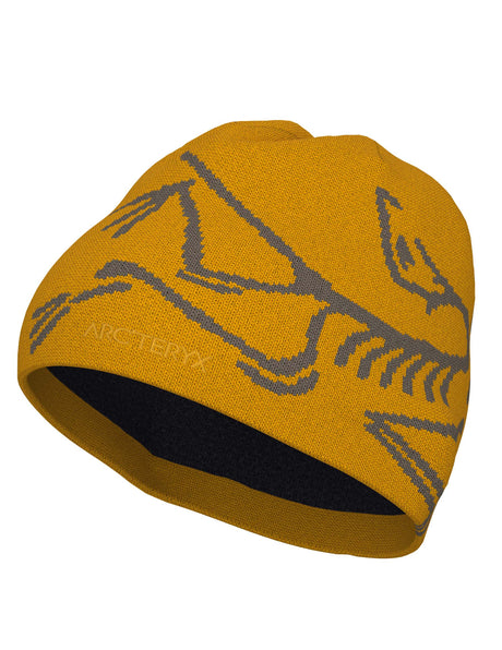 BirdHeadToque-A mustard yellow knit beanie hat featuring a gray knit Arc'teryx bird logo and the brand name 'ARC'TERYX' on the side, with a dark navy fleece lining visible at the opening.