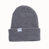 CoalTheStanleyBeanie-A dark gray ribbed knit beanie hat with a folded cuff, featuring a small white rectangular label on the front that reads 'coal'. The beanie is photographed against a clean, solid off-white background.