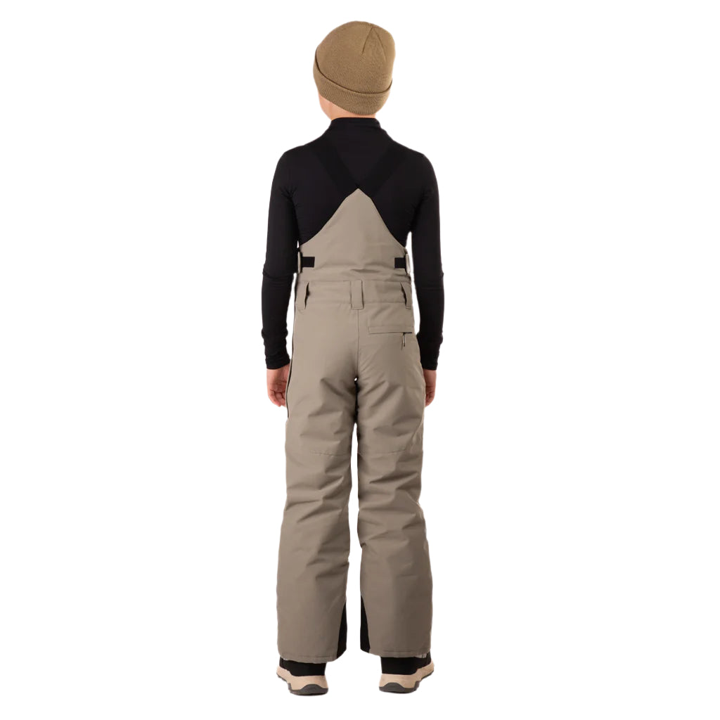 CooperBib-Person wearing beige bib overalls and a black long-sleeve shirt on a white background