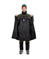DescentJacket-A man wearing a colorblock snowboard jacket in olive green and black, paired with a red knit beanie, green-tinted ski goggles, and black gloves, against a plain white background.