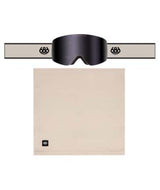 FoundationGogglePack-A pair of black ski goggles with a wide beige strap, shown above a matching beige neck gaiter. The goggles feature a dark tinted lens and a strap with a circular logo, while the neck gaiter has a small square logo in the lower left corner.