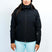 GaiaWomensInsulatedJacket-A woman modeling a black ski jacket with a high collar and front zipper, paired with light blue ski pants and a dark beanie with goggles, against a plain white studio background.