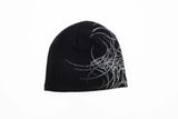 GeneralSkully- A black knit beanie hat featuring a white abstract line-art graphic on the left side and a small yellow 'public' logo on the lower right edge, shown against a plain white background.