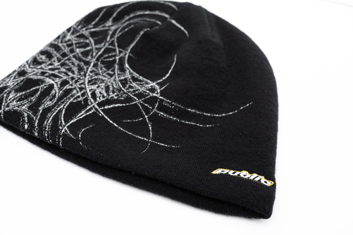 GeneralSkully- A black knit beanie hat featuring a white abstract line-art graphic on the left side and a small yellow 'public' logo on the lower right edge, shown against a plain white background.