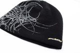 GeneralSkully- A black knit beanie hat featuring a white abstract line-art graphic on the left side and a small yellow 'public' logo on the lower right edge, shown against a plain white background.