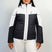 HelenaWomensInsulatedJacket-A woman modeling a colorblock ski jacket in white and black, paired with white ski pants, against a light gray studio background.