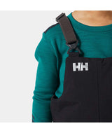 KidsRider2InsulatedBib- A young child wearing black Helly Hansen snow bib overalls over a teal long-sleeve shirt, standing against a light gray studio background.