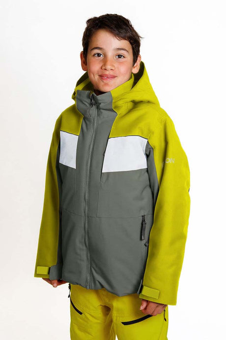 KrakenBoysInsulatedJacket-A young boy wearing a kids' ski jacket and matching pants. The jacket is olive green with a gray chest panel and white shoulder accents, and the brand 'KARBON' is visible on the upper right sleeve.