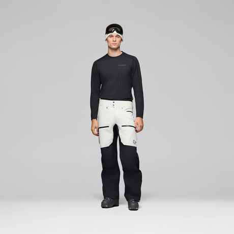 LofotenGore-TexProPant-Person wearing a black long-sleeve top and white pants with black accents on a gray background