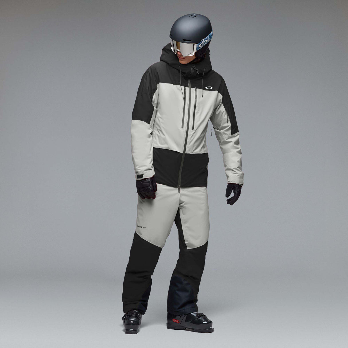 MCanopyProInsulatedJacket-A colorblock hooded jacket with a black upper section and sleeves, a light gray midsection, and a black lower section, featuring a full-zip front and a small white Oakley logo on the chest.