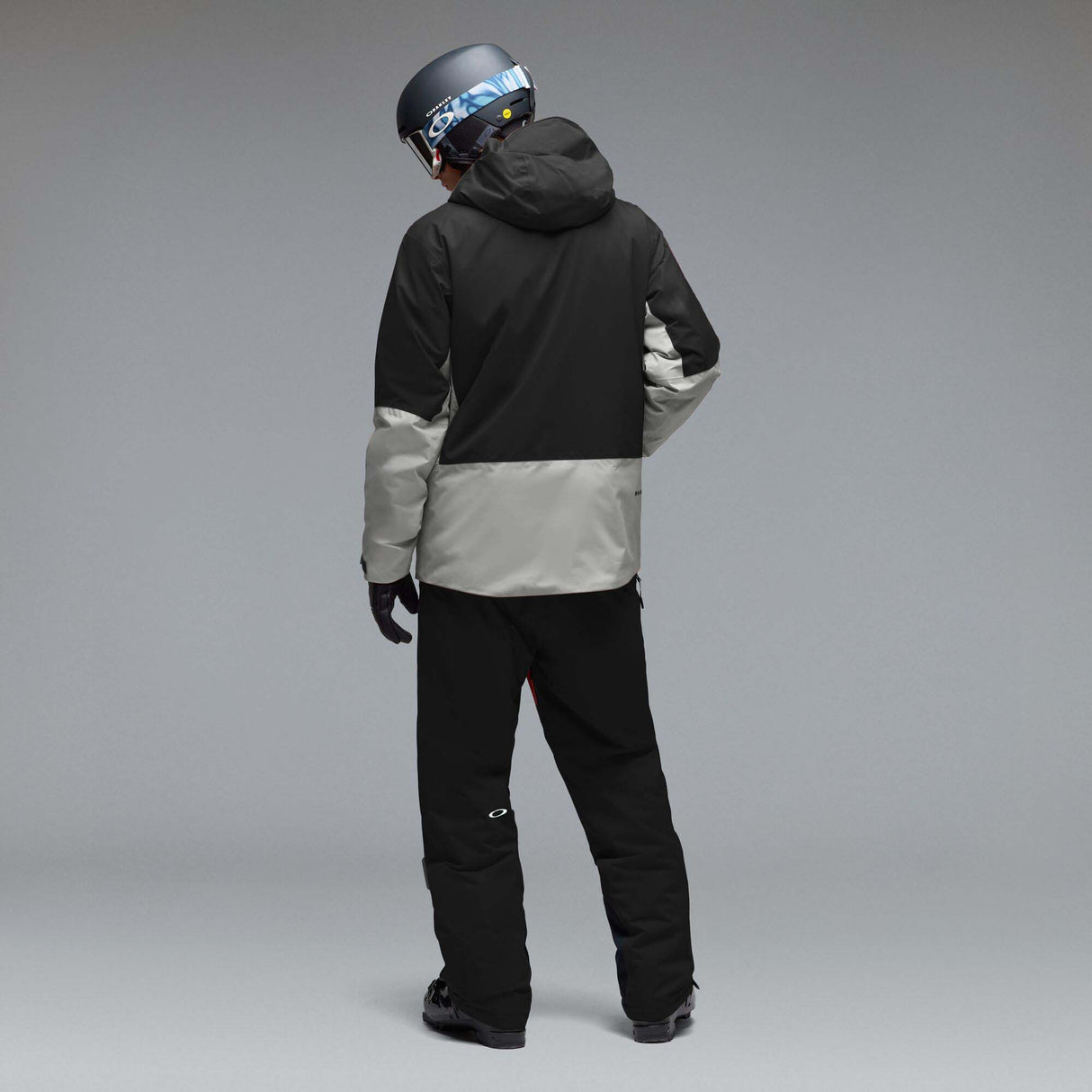 MCanopyProInsulatedJacket-A colorblock hooded jacket with a black upper section and sleeves, a light gray midsection, and a black lower section, featuring a full-zip front and a small white Oakley logo on the chest.