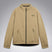MChannelJacket-A beige lightweight zip-up jacket with a black front zipper, black side zip pockets, and a small black Oakley logo on the left chest, displayed against a neutral gray gradient background.