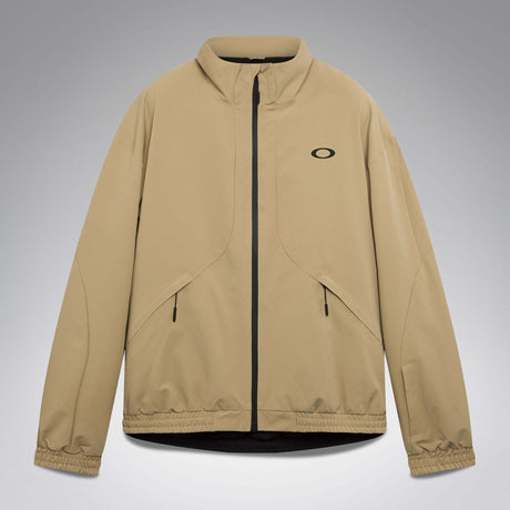 MChannelJacket-A beige lightweight zip-up jacket with a black front zipper, black side zip pockets, and a small black Oakley logo on the left chest, displayed against a neutral gray gradient background.