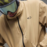 MChannelJacket-A beige lightweight zip-up jacket with a black front zipper, black side zip pockets, and a small black Oakley logo on the left chest, displayed against a neutral gray gradient background.