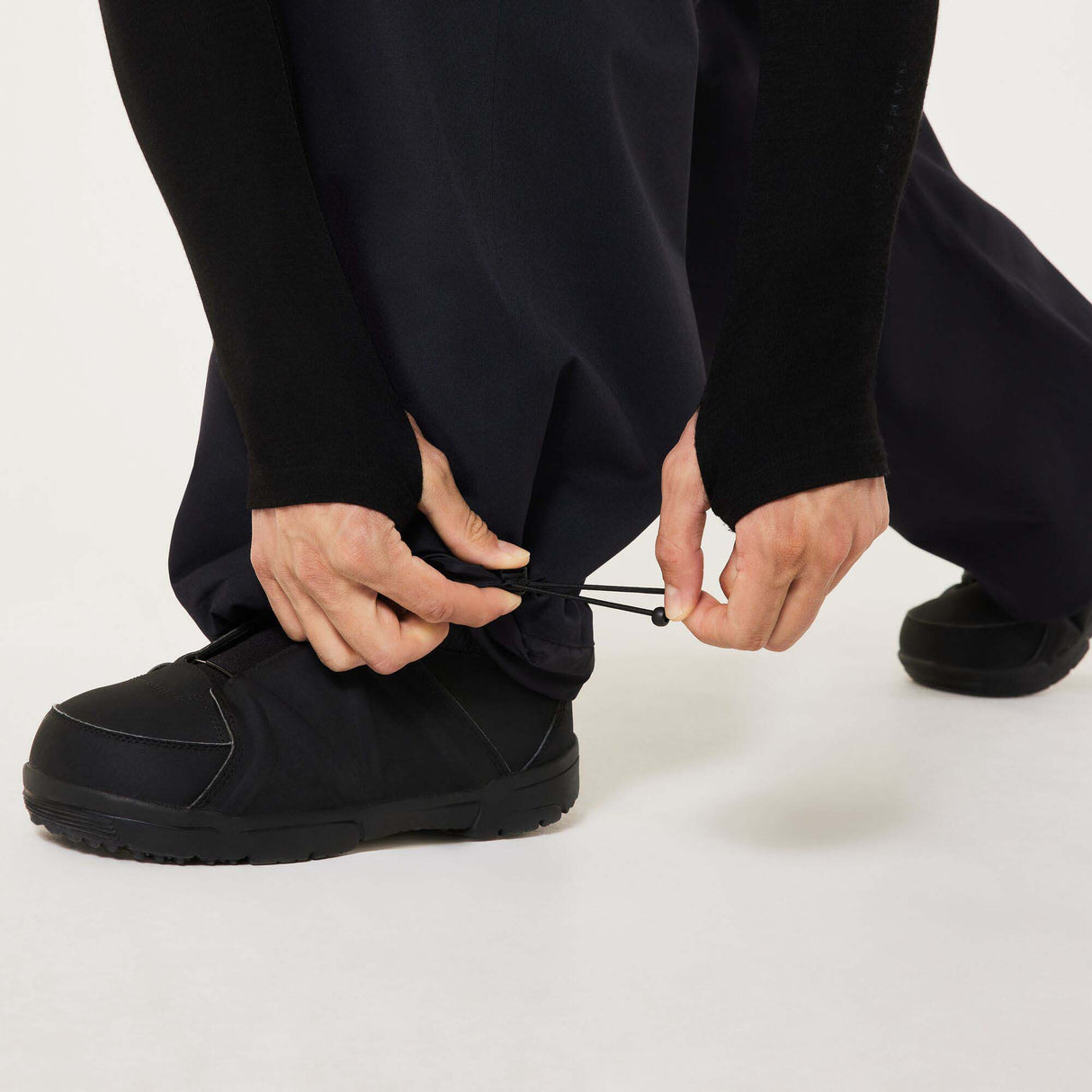 MChannelShellPant-Black wide-leg snow pants with an elastic drawstring waist and side pockets, shown on a light gray background.