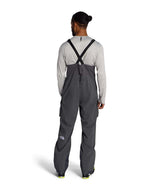 MFreedomBib- Man wearing grey bib overalls with The North Face logo on a white background