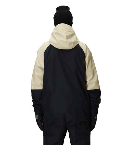 MHydraThermagraphJacket-A man wearing a color-blocked ski jacket in beige and black, along with black snow pants, gloves, and ski goggles, photographed against a solid white background.