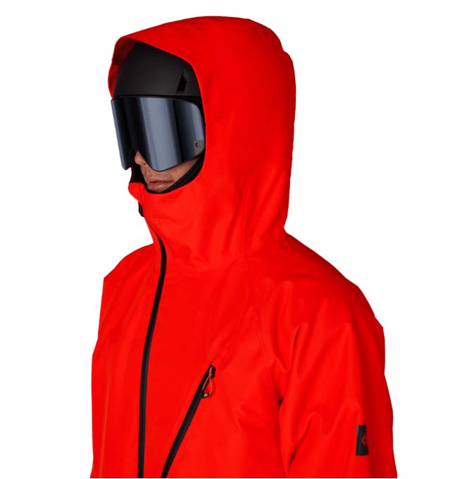 MHydraThermagraphJacket-A man wearing a bright red ski jacket with black zippers, black gloves, a black neck gaiter, and a red-and-black patterned bandana with goggles, photographed against a plain white background.