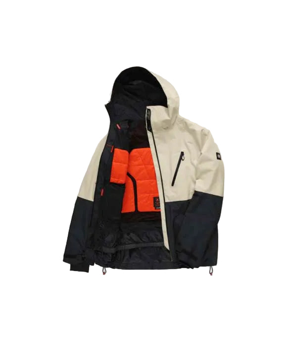 MHydraThermagraphJacket-A man wearing a color-blocked ski jacket in beige and black, along with black snow pants, gloves, and ski goggles, photographed against a solid white background.
