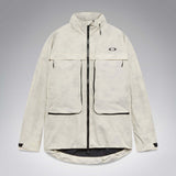 MMthodGlowShellJacket-A light beige technical jacket with black zippers, black piping details, and an Oakley logo on the left chest, displayed against a neutral gray background.