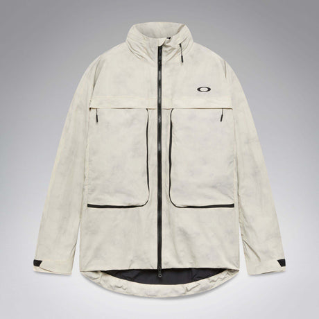 MMthodGlowShellJacket-A light beige technical jacket with black zippers, black piping details, and an Oakley logo on the left chest, displayed against a neutral gray background.
