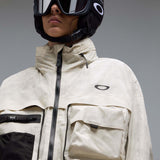 MMthodGlowShellJacket-A light beige technical jacket with black zippers, black piping details, and an Oakley logo on the left chest, displayed against a neutral gray background.