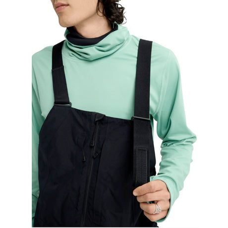 MReserveGORE-TEX2LBib-Person wearing a light green long-sleeve shirt and black overalls on a white background