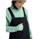 MReserveGORE-TEX2LBib-Person wearing a green shirt and black overalls on a white background