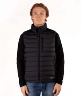 MSawyerPuffyVest-Man wearing a black puffer vest over a black shirt on a white background