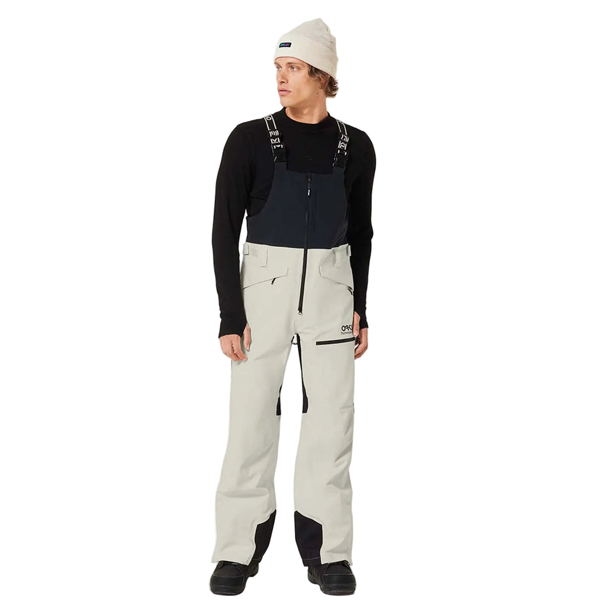 MTNPShellBib-Person wearing a black long-sleeve shirt, light gray pants, and a white beanie on a white background