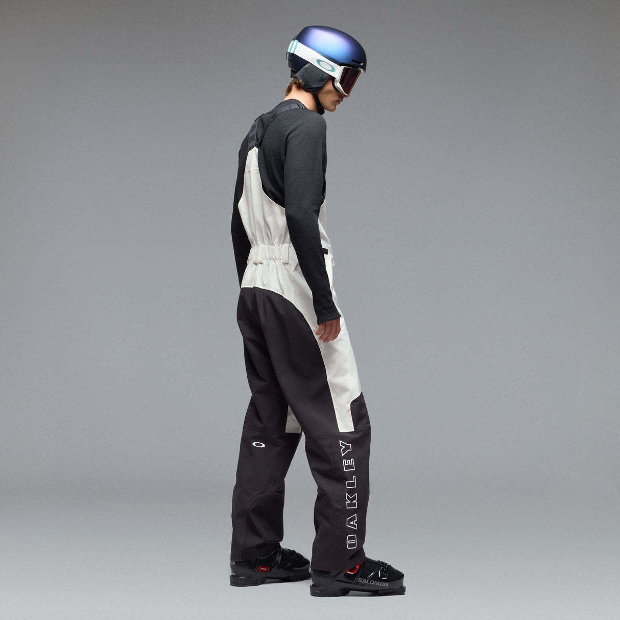 MTimberlineShellBib-A white and black technical snow bib with adjustable shoulder straps, a front zipper, and reinforced lower leg panels, shown against a neutral gray gradient background.